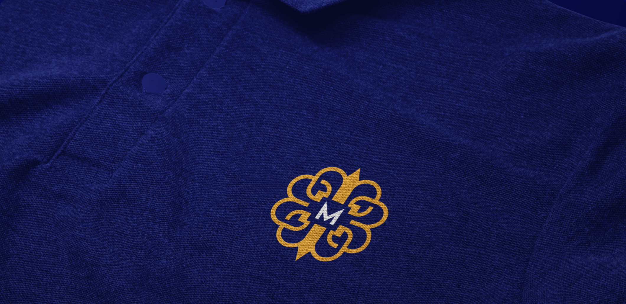 Gold Mercantile monogram embroidered on a navy polo shirt.